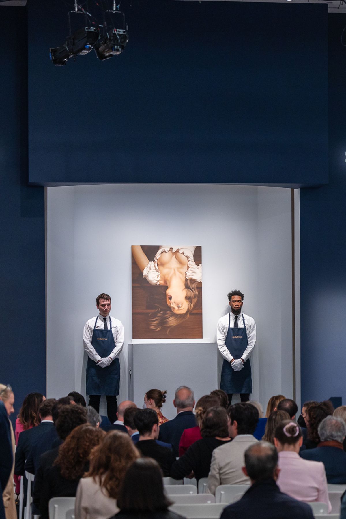 Two porters standing beside a painting in an auction room