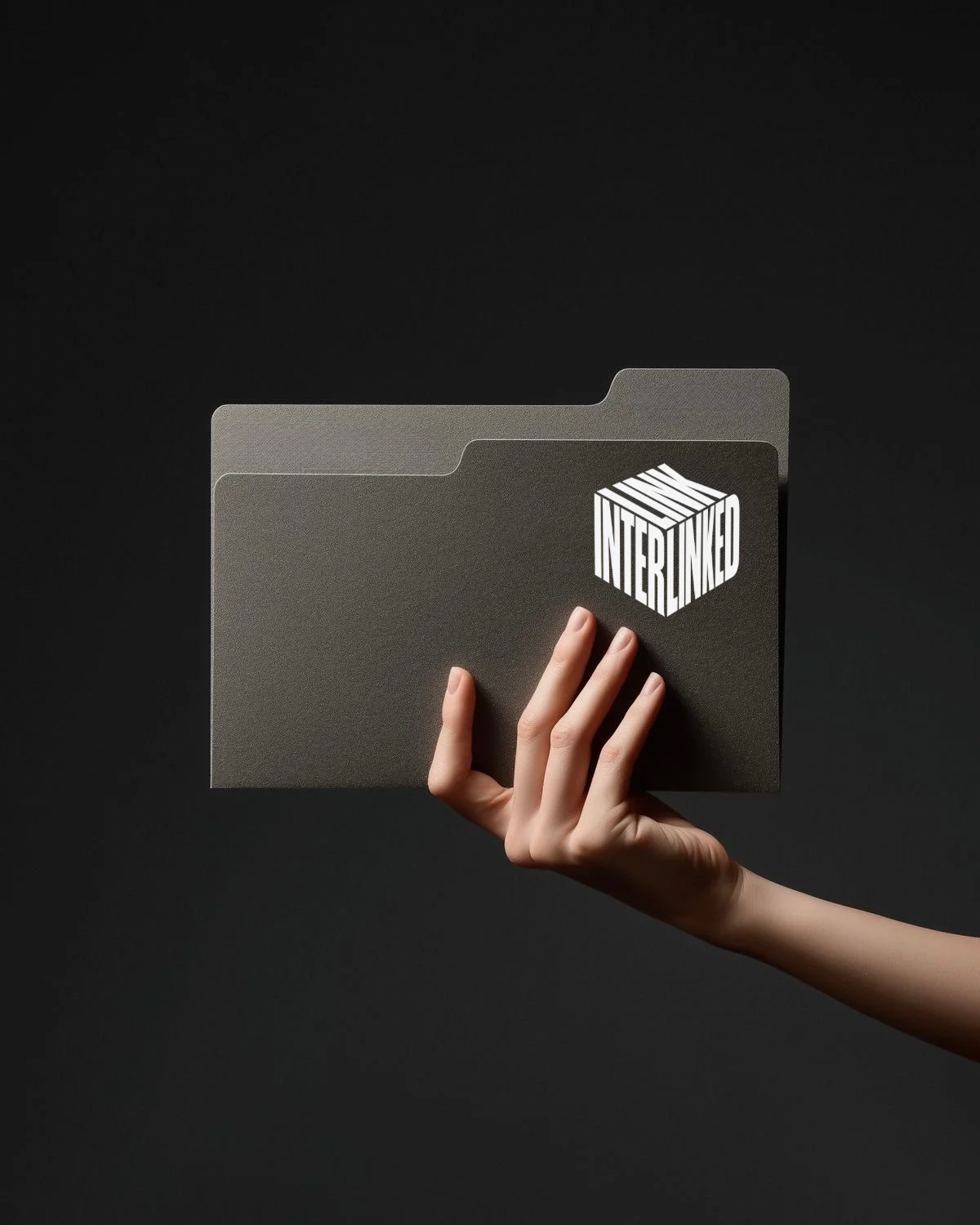 A hand holding a folder marked with the Interlinked cube
